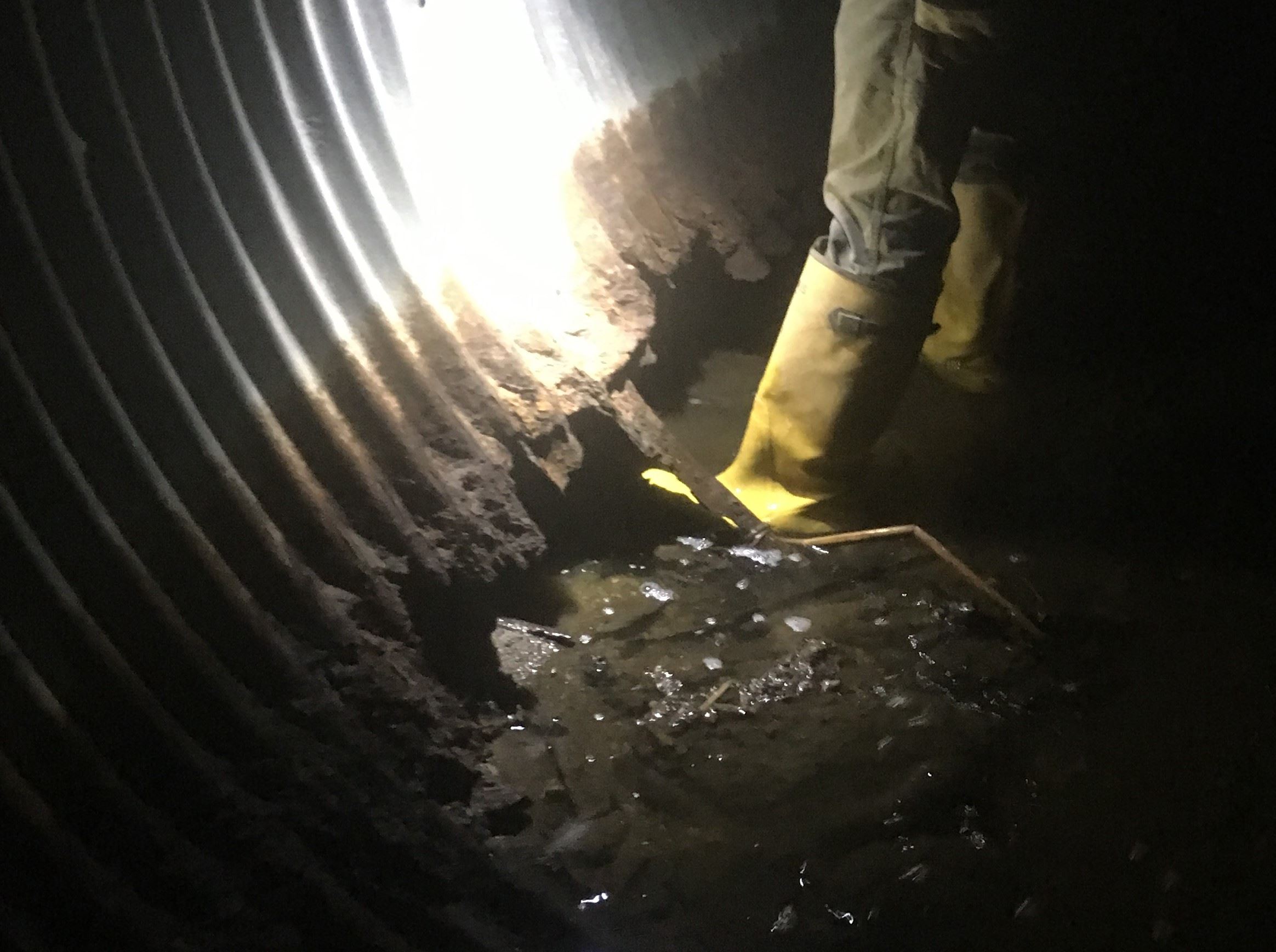 existing culvert with corrosion showing a boot though the bottom of pipe